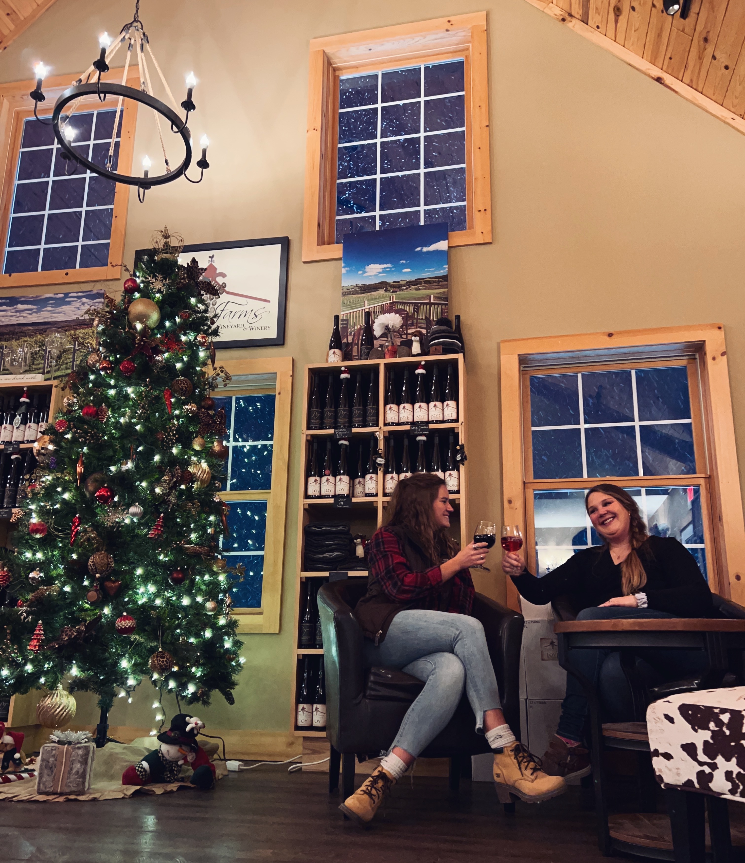 Two people drinking wine in the tasting room next to the Christmas tree.